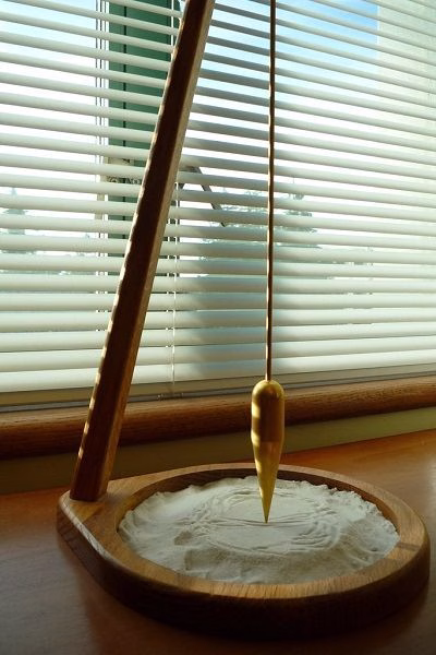 Crystal pendulum swinging over a wooden surface, symbolizing pendulum divination.