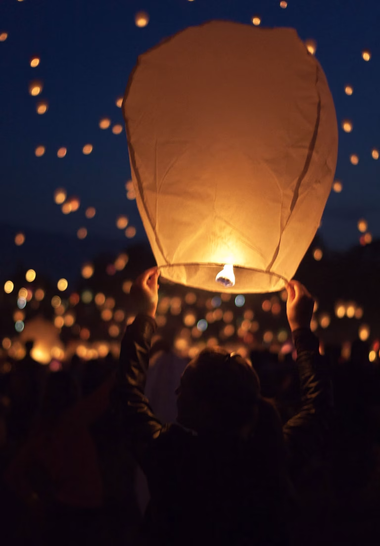 Person releasing a glowing paper lantern into a starry night sky, symbolizing emotional healing and moving on from a breakup.