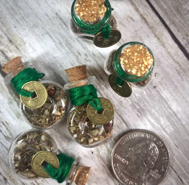 Coin wrapped in green thread with cinnamon sticks and clear quartz crystal on a wooden table, symbolizing money harmony spells.
