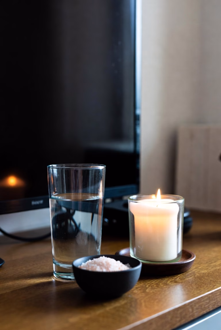 A quiet home altar with water, salt, and a white candle, symbolizing cleansing and spiritual reset after repeated bad luck.